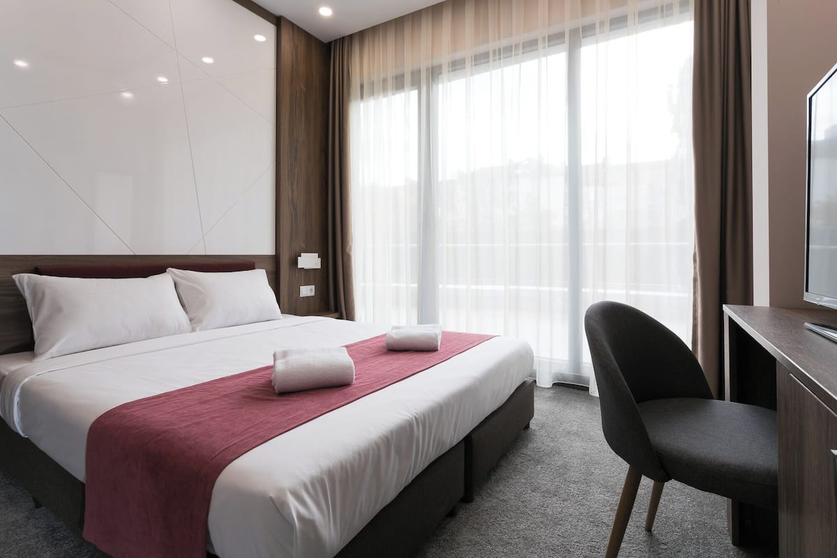 A hotel room with a large bed, a desk, and a chair.