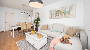 Una sala de estar moderna con un sofá blanco, una mesa de centro y un comedor con una mesa y sillas blancas.