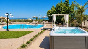 Ein Poolbereich mit Whirlpool, Liegestühlen und Sonnenschirmen.