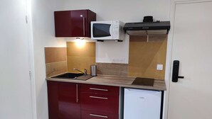 A compact kitchen with a microwave, stove, and dishwasher. - Studio Caesar - Air conditionning (Arles)