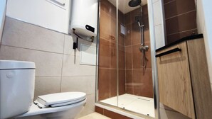 A modern bathroom with a toilet, a shower enclosure, and a cabinet. - Studio Caesar - Air conditionning (Arles)