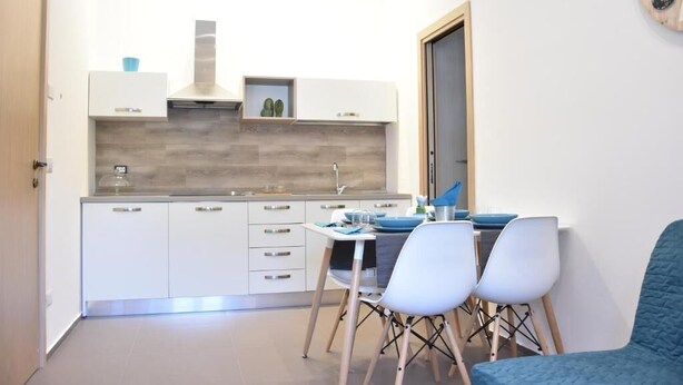 Une cuisine compacte avec des meubles blancs, un pare-feu en bois et un coin repas comprenant deux chaises et une table.