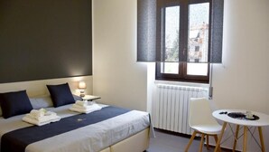 Une chambre à coucher comprenant un lit, une table de chevet, une chaise et une petite table avec une lampe.