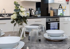 Une cuisine moderne avec des meubles blancs, un évier en acier inoxydable et un vase rempli de fleurs blanches posé sur le plan de travail.