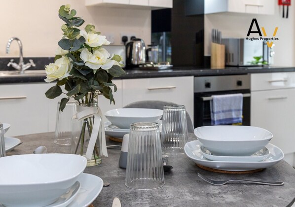 Una cocina moderna con armarios blancos, un lavamanos de acero inoxidable y un florero con flores blancas sobre la encimera.