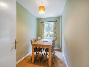 Un comedor con una mesa y sillas, una ventana con cortinas, y una lámpara en el techo.