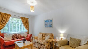 A living room with a sofa, armchair, and a table. - Spruce Cottage - UK46875 (Hartland)