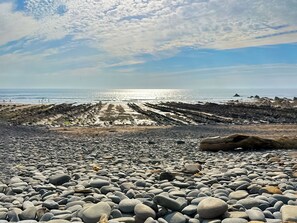 Una playa rocosa con cielo despejado y el océano al fondo.