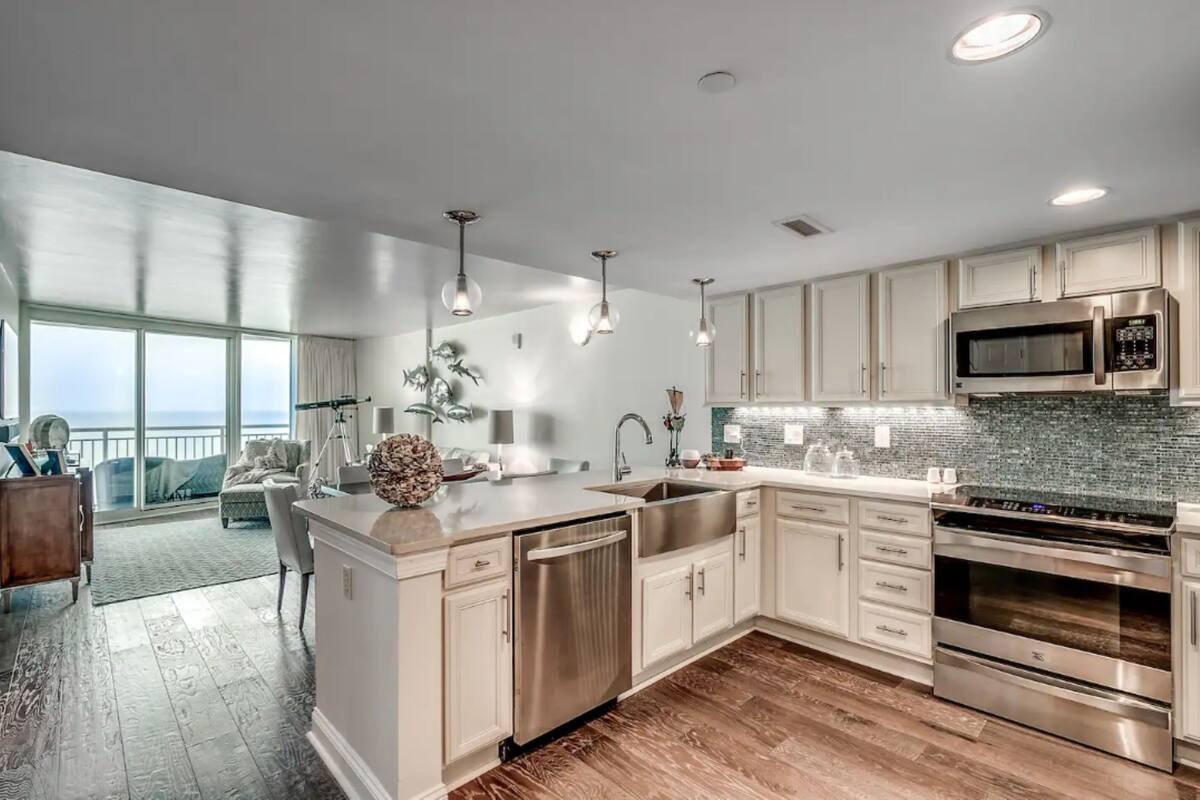A modern kitchen with stainless steel appliances, a large island, and a view to the outside.