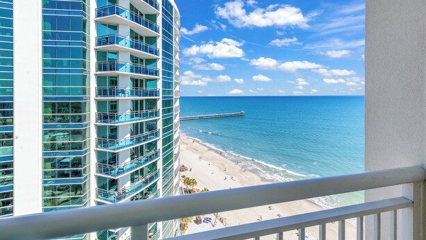 A high-rise hotel with multiple balconies overlooking a beach and ocean. - Condos at Sandy Beach by Beach Trips  (Myrtle Beach)