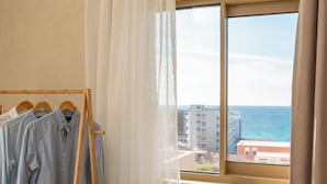 A room with a window view of the sea, a wooden hanger with clothes, and sheer curtains. - Açai Plant based Hotel (Rhodes)
