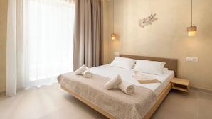 A modern hotel room with a large bed, a bedside table, and a wall-mounted light fixture. - Açai Plant based Hotel (Rhodes)