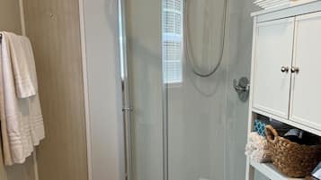 Enjoy a refreshing shower in the bathroom, featuring a glass-enclosed shower area, a toilet, and a cabinet with a woven basket.