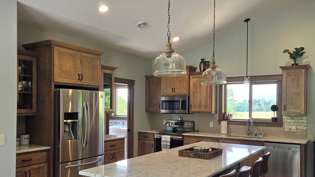 Una cocina moderna con armarios de madera, electrodomésticos de acero inoxidable y una isla grande con taburetes de bar.