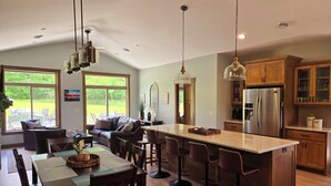 A modern kitchen with a central island, bar stools, and a dining area with a table and chairs.