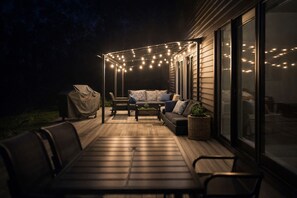 Une terrasse extérieure avec un canapé, des chaises et des guirlandes lumineuses.