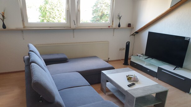 A modern living room with a grey sectional sofa, a small white coffee table, and a flat-screen TV on a stand. - Beautiful apartment in central Ingoöstadt (Ingolstadt)