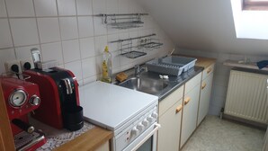 A kitchen with white cabinets, a red appliance, a sink, and a window. - Beautiful apartment in central Ingoöstadt (Ingolstadt)