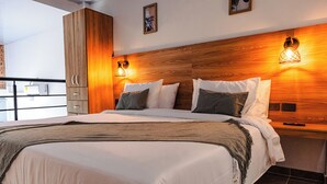 A modern hotel room with a large bed, wooden headboard, and two wall-mounted lights. - Central Suites by H&R (Villeta)