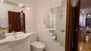 Ein modernes Badezimmer mit großem Spiegel, weißen Fliesen, Waschbecken und Toilette.