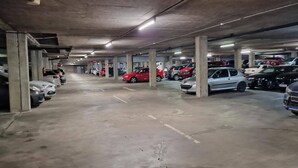 Eine mehrstöckige Tiefgarage mit Betonpfeilern und mehreren Reihen geparkter Autos.