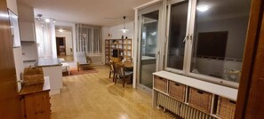 A spacious living area with a large window, a dining table, and a built-in TV shelf. - Graz Hideaway Retreat (Graz)