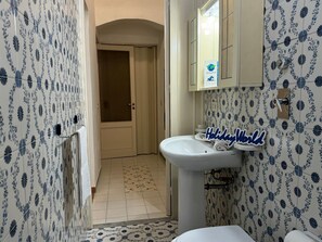 Classic bathroom with a pedestal sink and blue floral tiles.