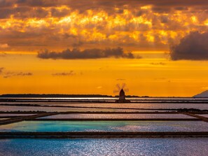 Stunning windmill stands amidst serene water bodies, reflecting the sky's warm hues.