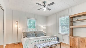 A bedroom with a bed, bedside lamp, wooden floor, ceiling fan, and a window with blinds. - 1 Mi to Beaches: Fairhope Home w/ Yard! (Fairhope)