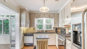 A modern kitchen with a central island, stainless steel appliances, and a window with a view of greenery. - 1 Mi to Beaches: Fairhope Home w/ Yard! (Fairhope)