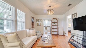 A living room with a sofa, coffee table, TV stand, and wooden flooring. - 1 Mi to Beaches: Fairhope Home w/ Yard! (Fairhope)