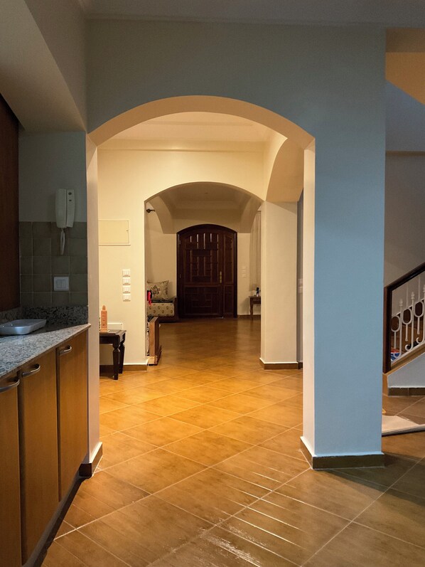 A spacious hallway with a tiled floor, an arched doorway, and a staircase on the right.