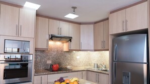 A modern kitchen with granite countertops, stainless steel appliances, and wooden cabinets. - Casa del Balcon (Baños de Agua Santa)