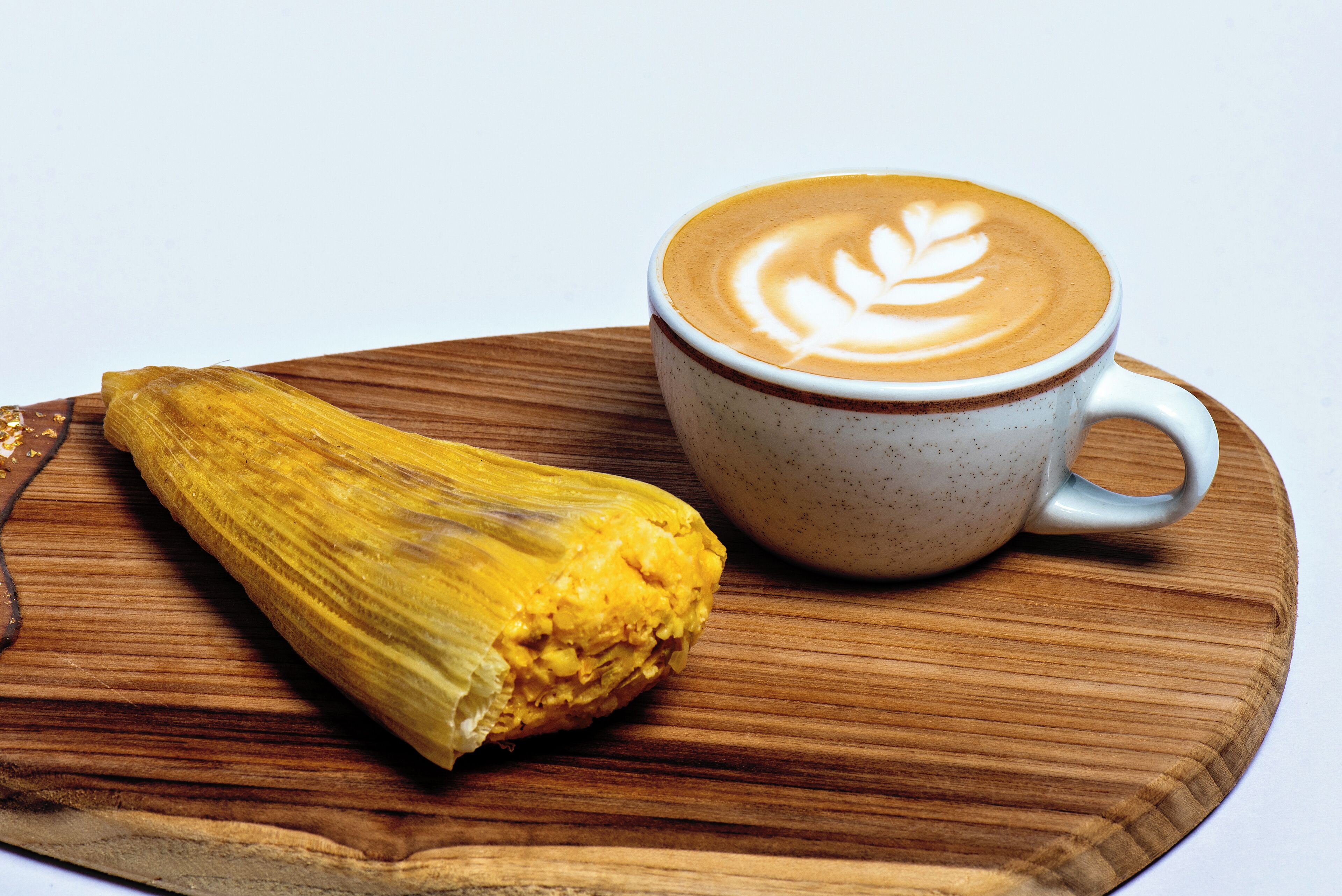 Ein Holzboden mit einer Banane und einer Kaffeetasse mit Latte-Art.