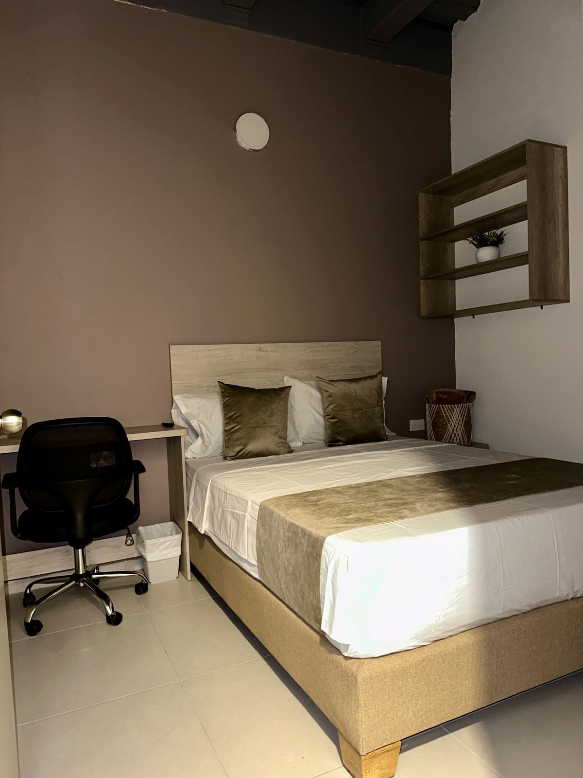 A bedroom with a bed, a desk, and a chair.