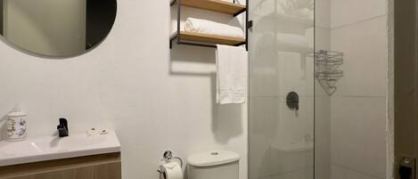Un baño moderno con inodoro, lavamanos y ducha.