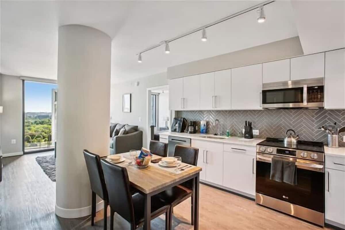 A modern kitchen with white cabinets, a stainless steel oven, and a herringbone-patterned backsplash.
