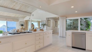 A spacious kitchen with a large island, built-in appliances, and a view of the sea. - Cove Watch by Avantstay A+ Views w/ Private Pool (La Jolla)