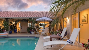 A poolside area with lounge chairs, a covered seating area, and potted plants. - Cove Watch by Avantstay A+ Views w/ Private Pool (La Jolla)