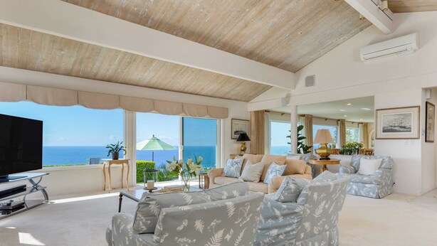 A spacious living room with a large TV, comfortable seating, and a view of the ocean. - Cove Watch by Avantstay A+ Views w/ Private Pool (La Jolla)