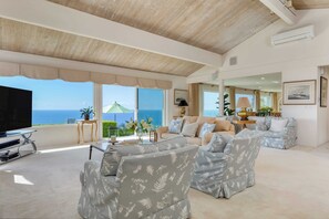 A spacious living room with a large TV, comfortable seating, and a view of the ocean. - Cove Watch by Avantstay A+ Views w/ Private Pool (La Jolla)