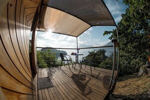 Una terraza de madera con una mesa y sillas, con vista a una masa de agua y vegetación.