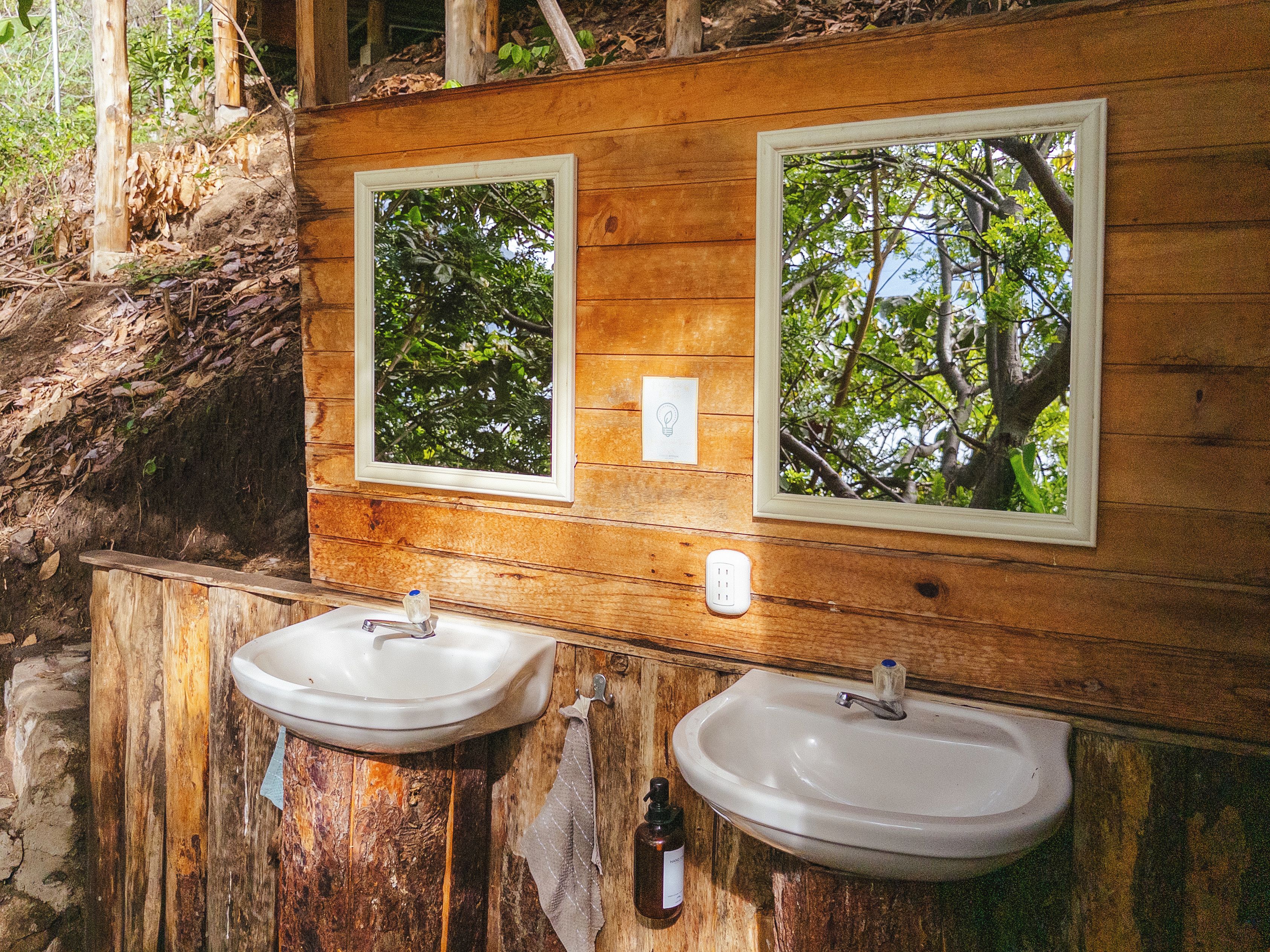 A rustic wooden bathroom with two sinks, a mirror, and a window.