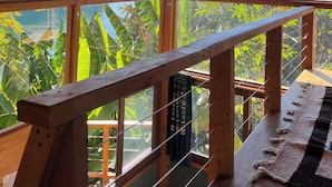 A wooden cabin with large windows offering a view of mountains and a lake.