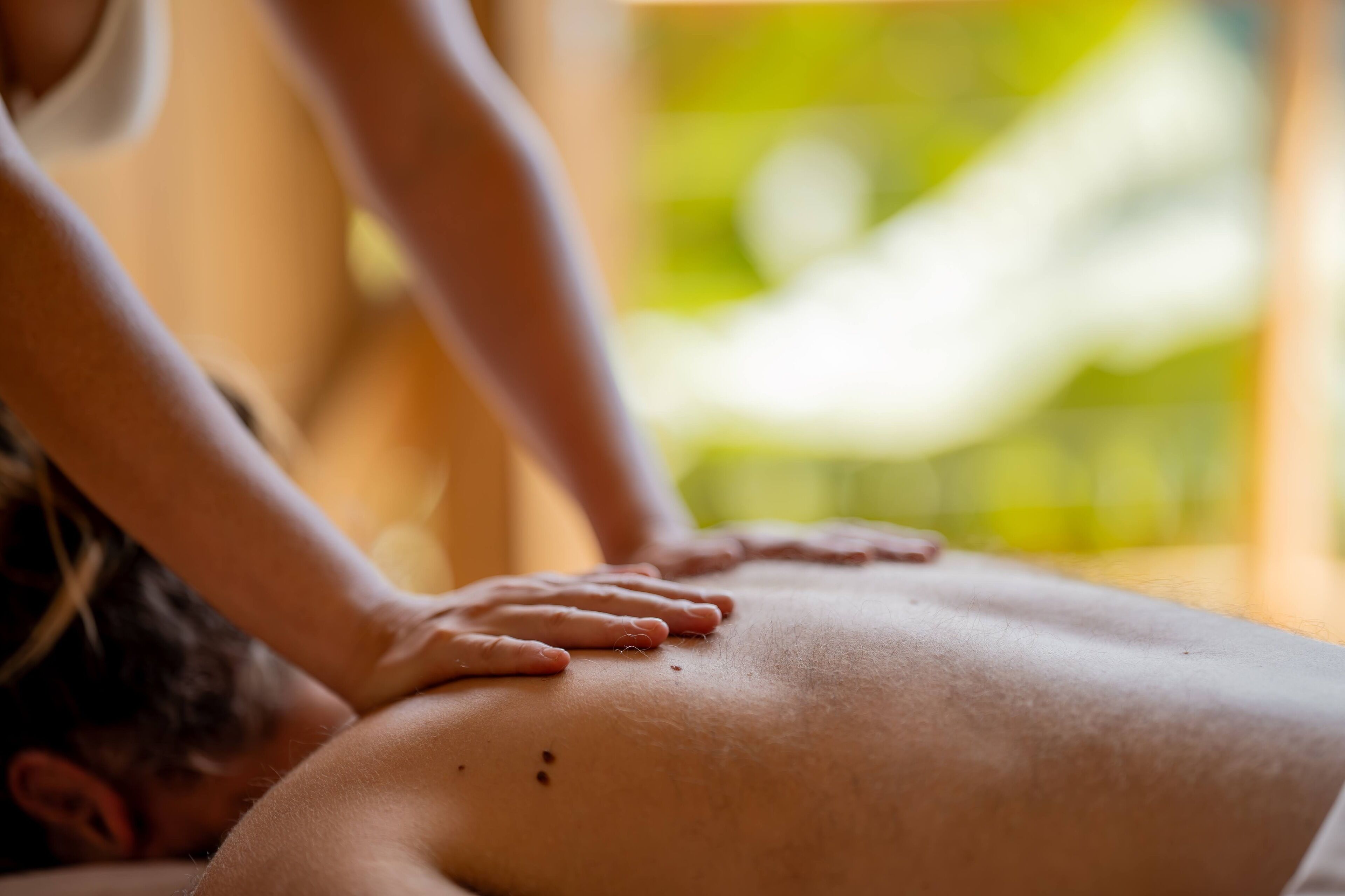 A massage therapy session with a focus on the therapist's hands on a client's back.