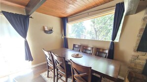 A dining area with a wooden table and chairs, a stone fireplace, and a window with curtains. - Hidden Jewel for the Family, Near the Broadmoor (Colorado Springs)
