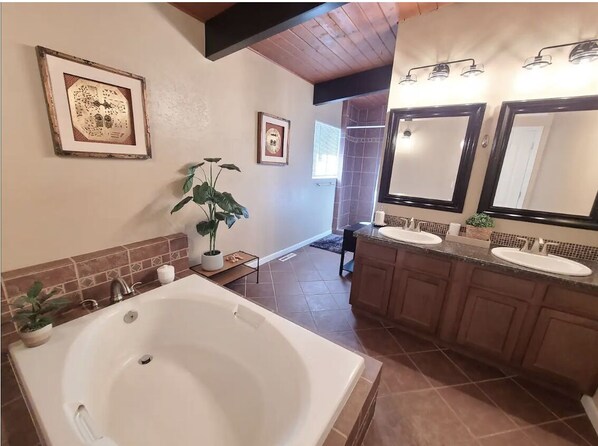 A bathroom with a large bathtub, two sinks, and a mirror.
