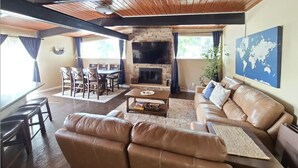 A living room with a fireplace, leather sofas, a coffee table, and a dining area with chairs and a table. - Hidden Jewel for the Family, Near the Broadmoor (Colorado Springs)