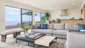 A modern living room with a large sofa, a coffee table, and a view of the ocean. - Jewel by Avantstay Panoramic Ocean Views in La Jolla! (La Jolla)