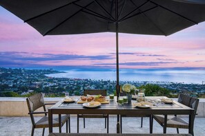 Una mesa lista para el desayuno con vistas al océano y al paisaje urbano.